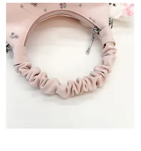 Gros plan sur la bandoulière froncée et l'imprimé floral du sac à main rose