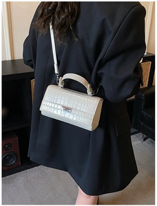 Lifestyle shot showing cream crocodile pattern handbag paired with a black blazer