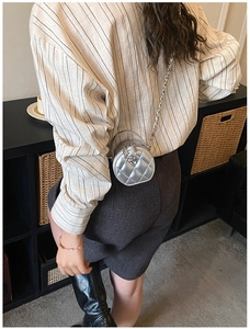 Détail du mini sac bandoulière cylindrique argenté avec matelassage et breloque fleur