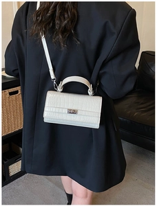 Detailed view of white crocodile pattern leather handbag with silver metallic buckle