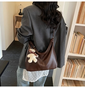 Detailed close-up of dark brown hobo tote bag featuring a cute teddy bear charm