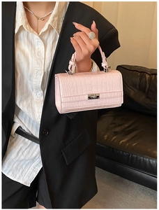 Detail of light pink crocodile pattern handbag with silver metal rotating lock