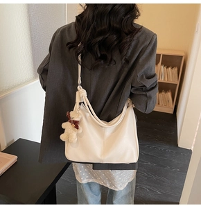 Detail of off-white textured leather tote bag with cute teddy bear plush charm