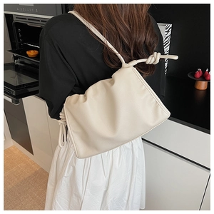 Close-up of creamy white pleated leather bag with knotted shoulder strap detail