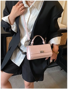 Close-up of pink croc-effect mini bag with silver lock worn by model in black blazer