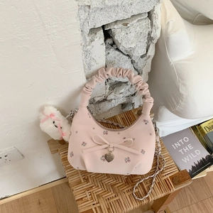 Détail du sac rose avec broderie florale, nœud et pendentif en métal en forme de cœur