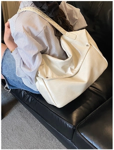 Detail showing off-white oversized faux leather shoulder bag with pleated texture and silver buckle