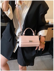 Pink croc-embossed small square bag styled as a crossbody on a fashion model