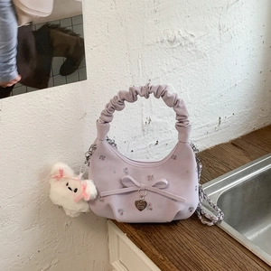 Détail du sac lavande avec nœud, pendentif en cœur et breloque petit chien en peluche
