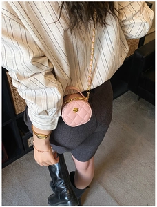 Gros plan du mini sac rond rose matelassé avec chaîne dorée et détail de fleur en métal