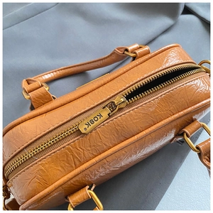 Detail of a vintage brown leather bowling bag with shiny pleated texture and golden zipper