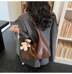 Detail view of large dark brown leather hobo bag featuring a cute teddy bear charm