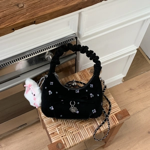 Détail d'un sac à main en velours noir avec broderie florale violette et anse froncée