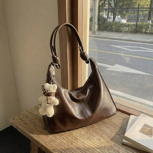 Retro deep brown leather tote bag with knotted straps and a plush bear charm decoration