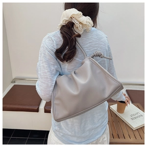 Detail of grey pleated shoulder bag with unique knotted strap and soft leather texture