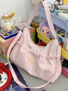 Détail du sac à épaule en nylon rose plissé avec écusson logo et bandoulière réglable