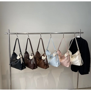 Close-up of leather tote bags in various colors hanging on a metal rack with bear charms