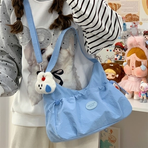 Détail du sac bandoulière en nylon bleu clair avec poche à cordon et breloque lapin