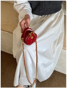 Gros plan d'un petit sac rond matelassé rouge avec chaîne sur une robe blanche élégante
