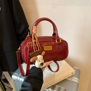 Retro red patent leather bowling bag with shiny wrinkled texture and puppy charm accessory