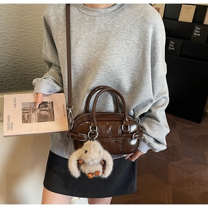 Polished dark brown leather bowling bag with plush rabbit charm in a vintage setting