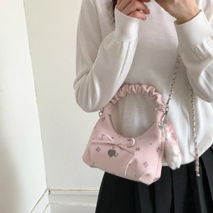 Vue détaillée du sac rose à fleurs avec nœud décoratif et pendentif cœur en métal