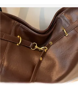 Close-up of vintage brown leather tote bag showing glossy texture and gold metal hardware
