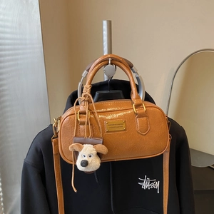 Vintage caramel patent leather bowling bag with gold plaque and plush dog charm accessory