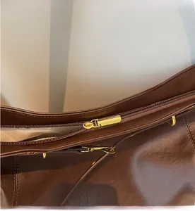 Detailed view of the smooth gold-tone zipper and textured brown leather on the tote bag