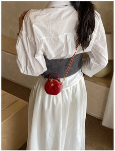 Détail du mini sac rond rouge matelassé avec fleur dorée et bandoulière chaîne sur modèle