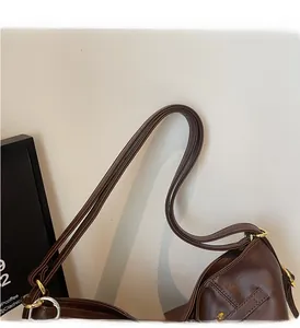 Close-up of durable padded handles and gold-toned metal rings on retro brown tote bag