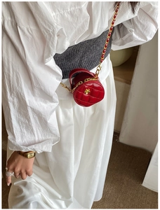 Détail du mini sac rond matelassé rouge avec fermoir fleur dorée sur chemise
