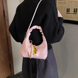 Close-up of pink ruched hobo bag with gold chain and colorful beaded charm detail
