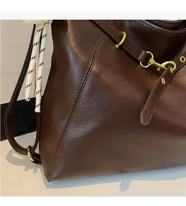 Detail of vintage brown leather tote bag showing gold hardware and stitching