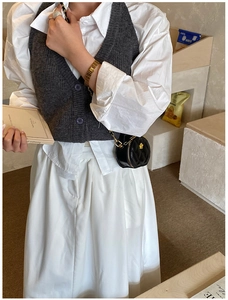 Détail d'un mini sac rond matelassé noir avec chaîne porté sur une chemise et un gilet