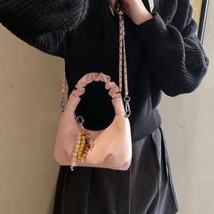 Detail of pink crescent bag with gathered handle, gold chain strap and wooden bead charm