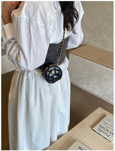 Détail du mini sac rond matelassé avec boucle fleur dorée porté à la taille en bandoulière