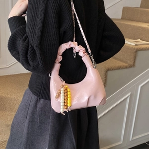 Detailed view of pink pleated handbag with silver chain and colorful bead charm decoration
