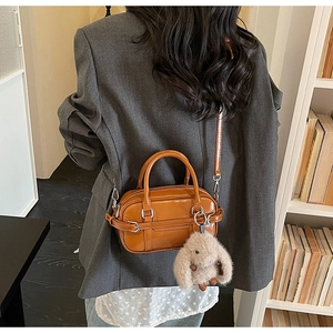 Detail of caramel leather boston bag with belt buckle and cute plush rabbit charm