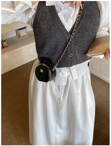 Détail du mini sac rond matelassé noir avec chaîne dorée porté par le mannequin