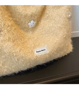 Detail of beige fleece tote bag featuring star button and delicate lace brand label