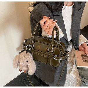 Olive green patent leather handbag with silver buckle and plush bunny charm on model