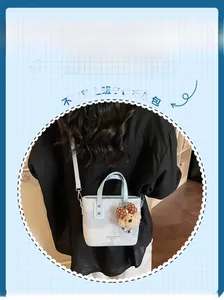 Détail du sac seau bleu clair et beige avec breloque ours en peluche et bandoulière