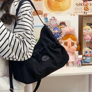 Détail du grand sac cabas noir avec plis à cordon et logo de la marque sur le côté