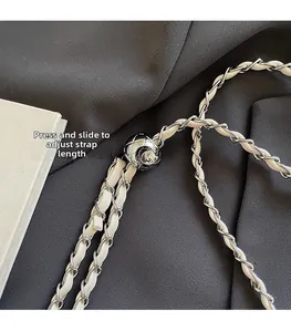 Detailed macro view of silver metal ball adjustment buckle on a white leather chain strap