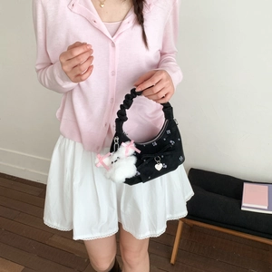 Détail du sac à main noir brodé avec texture velours, nœud papillon et pendentif lapin