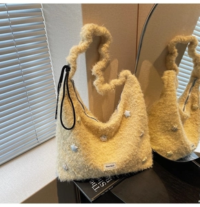 Detail of plush cream-colored star tote bag with wavy shoulder strap on black surface