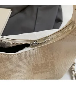 Close-up of the smooth silver metal zipper and textured off-white faux leather on the bag