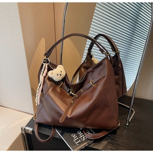 Detail of vintage brown leather tote bag showing soft texture and bear ornament
