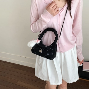 Détail du sac dumpling en velours noir avec broderies de fleurs et charm lapin en peluche
